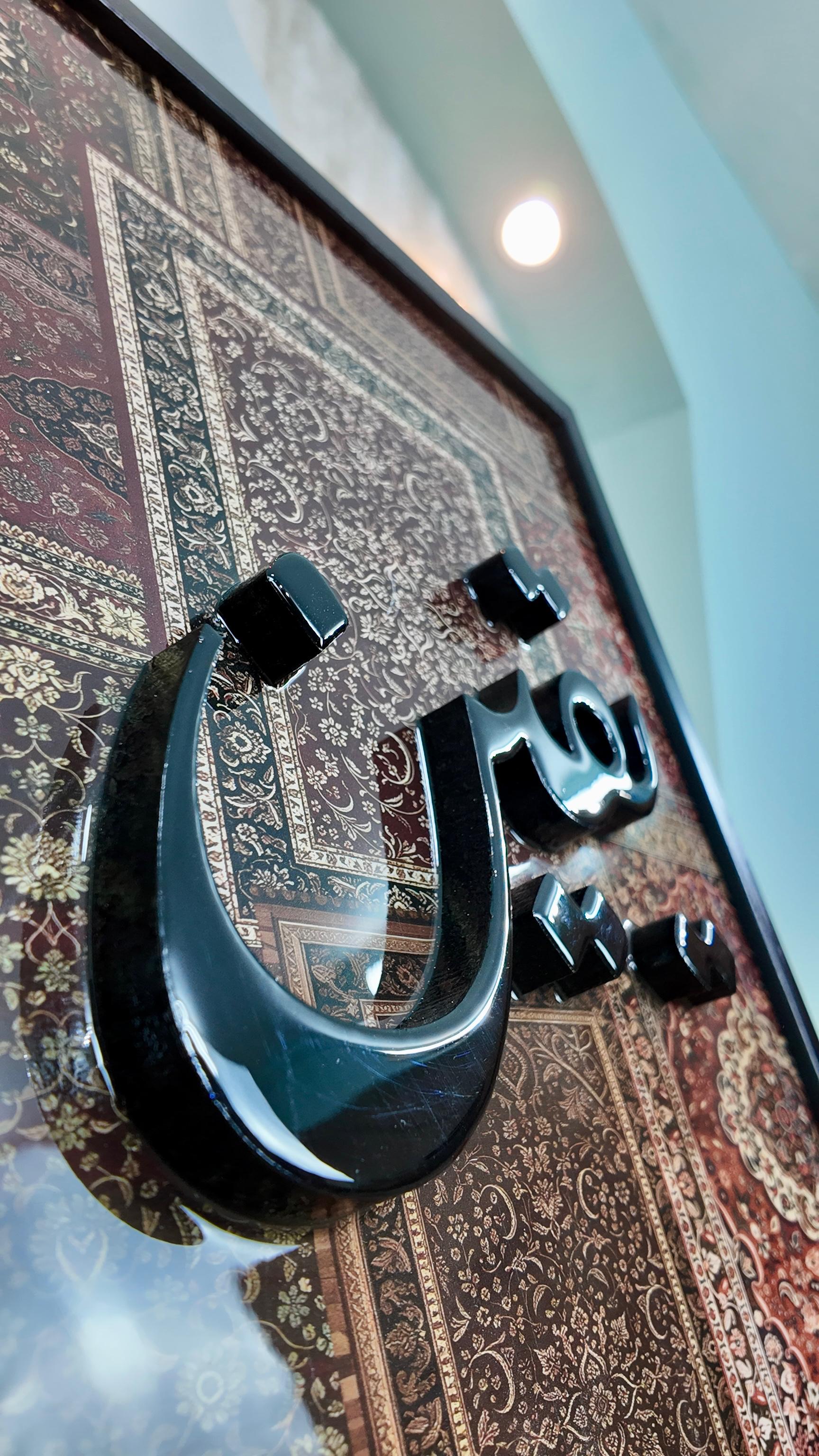 Gros plan sur la calligraphie “Al Yaqin” en relief 3D, sublimée par une couche de résine transparente qui recouvre tout le tableau et met en valeur la profondeur des lettres ainsi que la richesse du fond inspiré d’un tapis oriental.